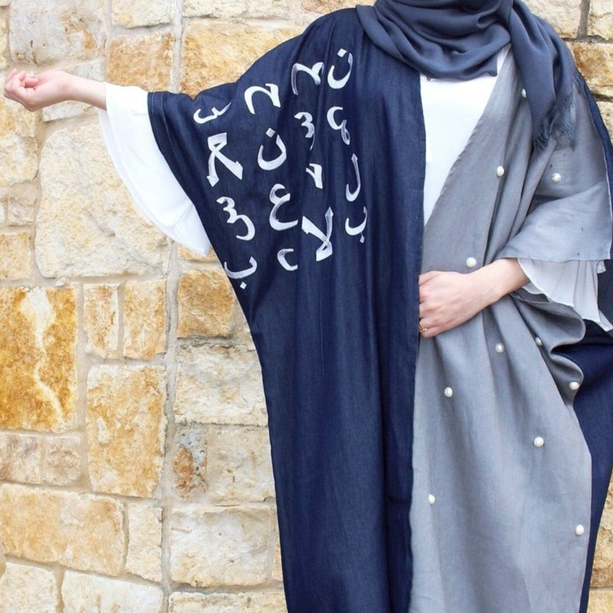 Person wearing the blue abaya with denim material and Arabic letters.